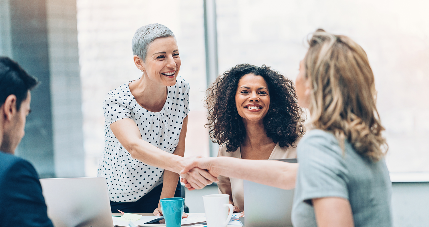 2 businesswomen shalke hands in a meeting