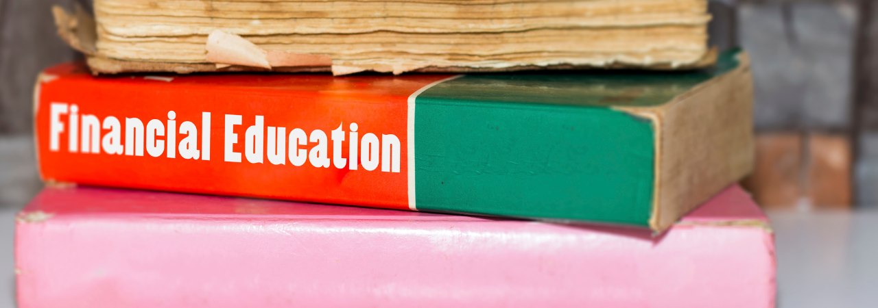 Close up on stack of books, with focus on middle book - a green and red textbook with title 'Financial Education'