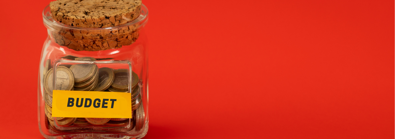 Money jar full of coins, labelled 'budget', against red background