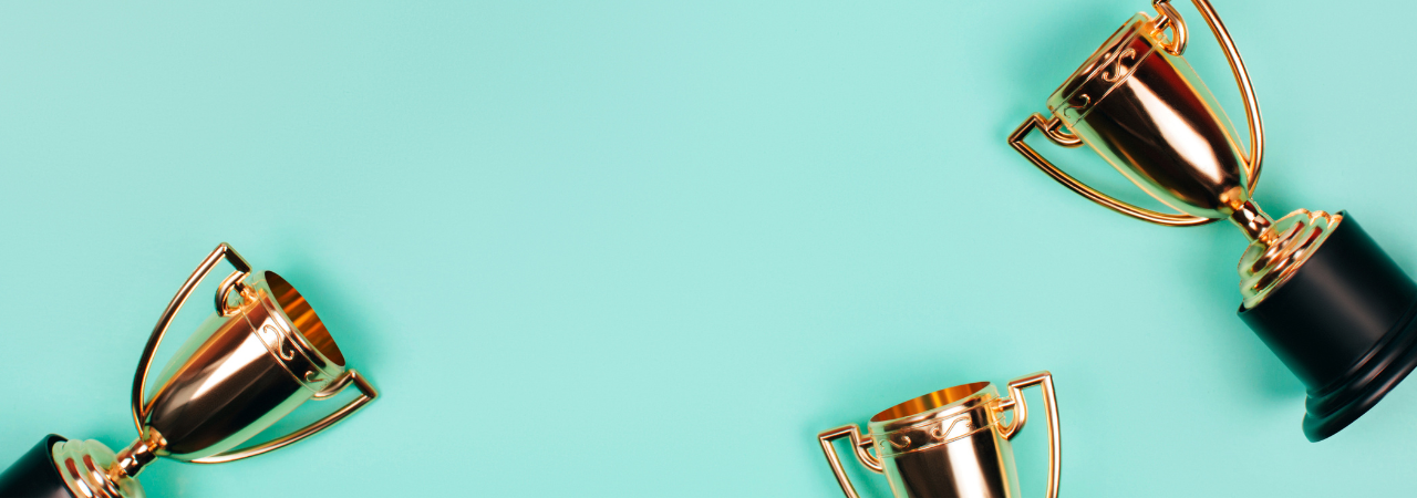 Mint green background with gold trophies scattered in foreground