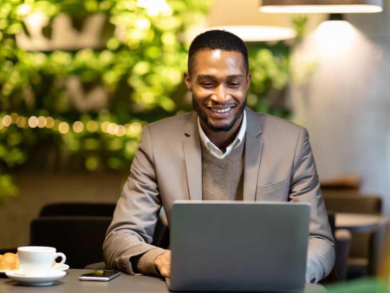 man smiles while looking at laptop