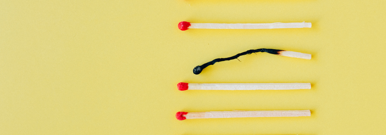 yellow background with 4 matches laying in a line. second match is burned out.