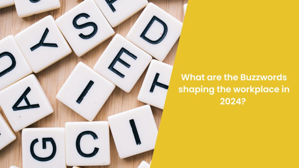 scattered miscellaneous letter tiles across surface, with yellow overlay showing blog title, 'What are the Buzzwords Shaping the Workplace in 2024?'