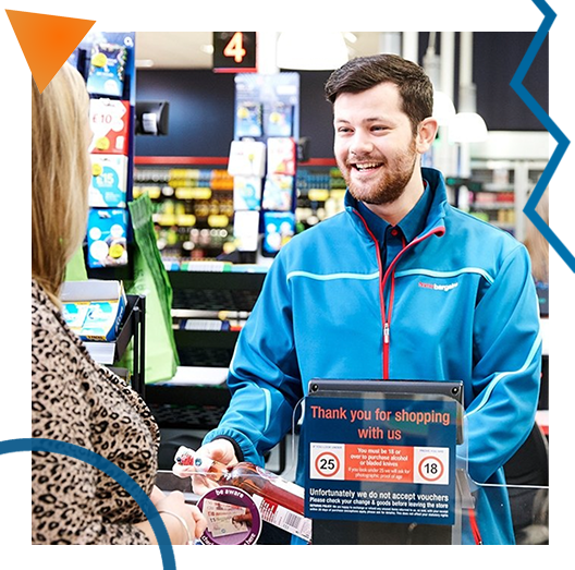 Smiling Home Bargains employee serving woman at a till