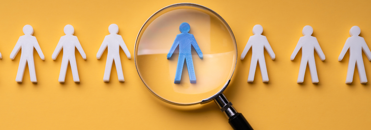 a yellow background image with symbols of people, the one in the middle is blue and has a magnifying glass over it.