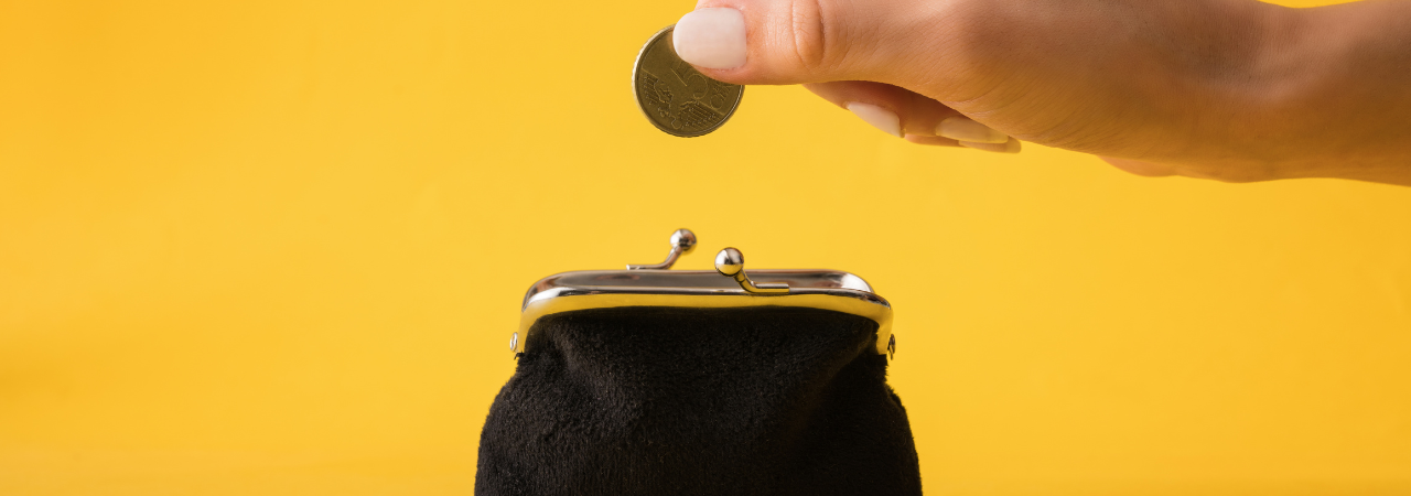 an image with a yellow background, a black purse in the middle with a hand about to put the coin into the purse .